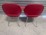two red chairs sitting next to each other in front of a wall