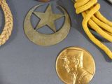 a gold medal, a medal, a rope, and a medal laying on a table