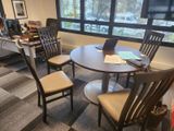 une table avec des chaises et un ordinateur portable posé dessus, dans un bureau
