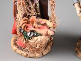 two figurines of a man and a woman holding baskets of food