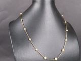 un mannequin noir portant un collier de perles dorées