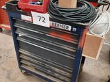a man that is standing in a garage with a tool cart