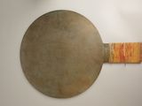a large metal plate with a wooden handle on the wall