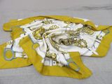 a yellow scarf with a chain on it laying on a bed