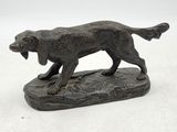 statue d'un chien tenant un os dans la gueule, posé sur un rocher