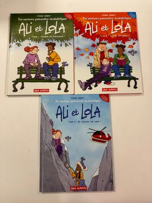 Trois livres pour enfants sont posés sur une table devant un mur blanc.