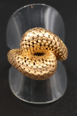 un gros plan d'une bague en forme de serpent en or posée sur une surface noire