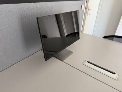 a computer monitor sitting on a desk in a cubicle