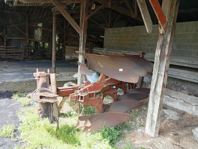 un tracteur qui se trouve dans l'herbe près d'un bâtiment