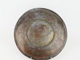an old metal bowl on a stand on a white surface