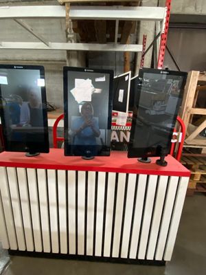 three monitors on a red and white stand in a warehouse