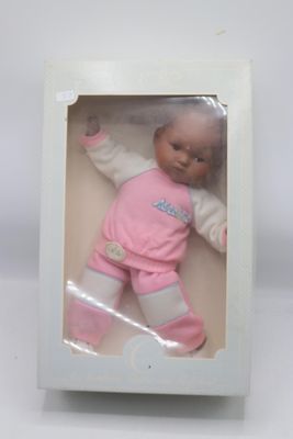 poupée dans une boîte blanche, vêtue d'une tenue rose et de chaussures roses