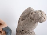 a clay sculpture of a man sitting on a chair next to a statue of a dog