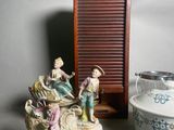 two figurines sitting on a table next to a bowl and plate