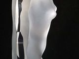 sculpture of a woman sitting on a glass base on a black background