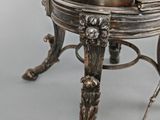 an antique silverplated table with a glass top and metal legs