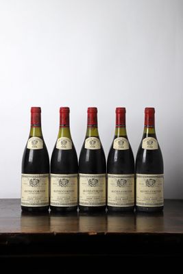 six bottles of wine lined up on a wooden table