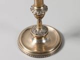 a silver candle that is on top of a silver plate