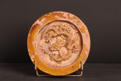 une image représentant une assiette ornée d'un dragon, posée sur un socle