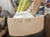 une boîte en carton sur laquelle est accrochée une pancarte, posée au milieu d'une pile d'autres boîtes