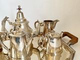a silver tea set on a tray on a table