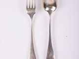 two spoons and a fork on a white surface