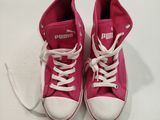une paire de baskets montantes roses avec des lacets blancs, sur un fond blanc