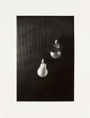 black and white photograph of two light bulbs hanging from a wall