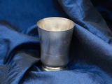 a silver cup that is sitting on a blue cloth
