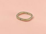 un gros plan d'une bague en or posée sur une surface rose