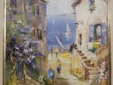 tableau à l'huile encadré représentant un village en bord de mer avec un voilier