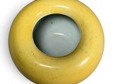 a yellow vase with a green inside on a white surface