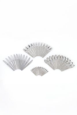 four pieces of silverware are arranged on a white surface