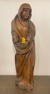 statue en bois représentant une femme tenant une fleur jaune dans ses mains