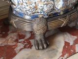 a silver turtle sitting on top of a blue and white bowl