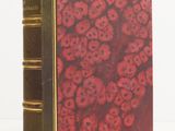 an old book with red flowers on it sitting on a white surface