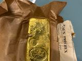 someone is holding a gold bar in their hand on a piece of paper