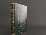 un vieux livre à la couverture verte et aux bords dorés