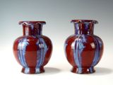 une paire de vases rouges et bleus posés sur une table blanche