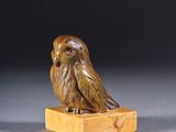 a small carved bird on a wooden block
