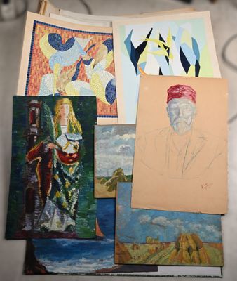 many paintings on a table with a cat in the background
