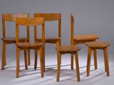 trois chaises en bois et une table sur laquelle est posé un livre