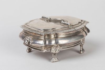 un plat ancien en argent avec un couvercle, posé sur un socle, sur une surface blanche