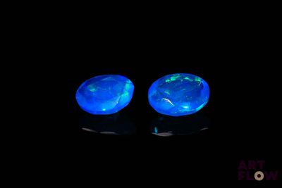 deux oplites bleues qui brillent dans le noir sur une surface noire