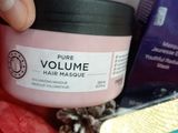 a person holding a jar of hair mask next to a package of hair products