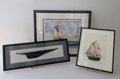 three framed pictures of sailboats on display on a table