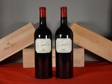 two bottles of red wine sitting next to each other on a table