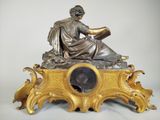 a statue of a man reading a book on top of a clock