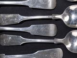 six spoons that are sitting on a black surface