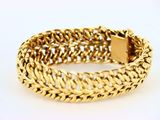 gros plan d'un bracelet en or sur une surface blanche